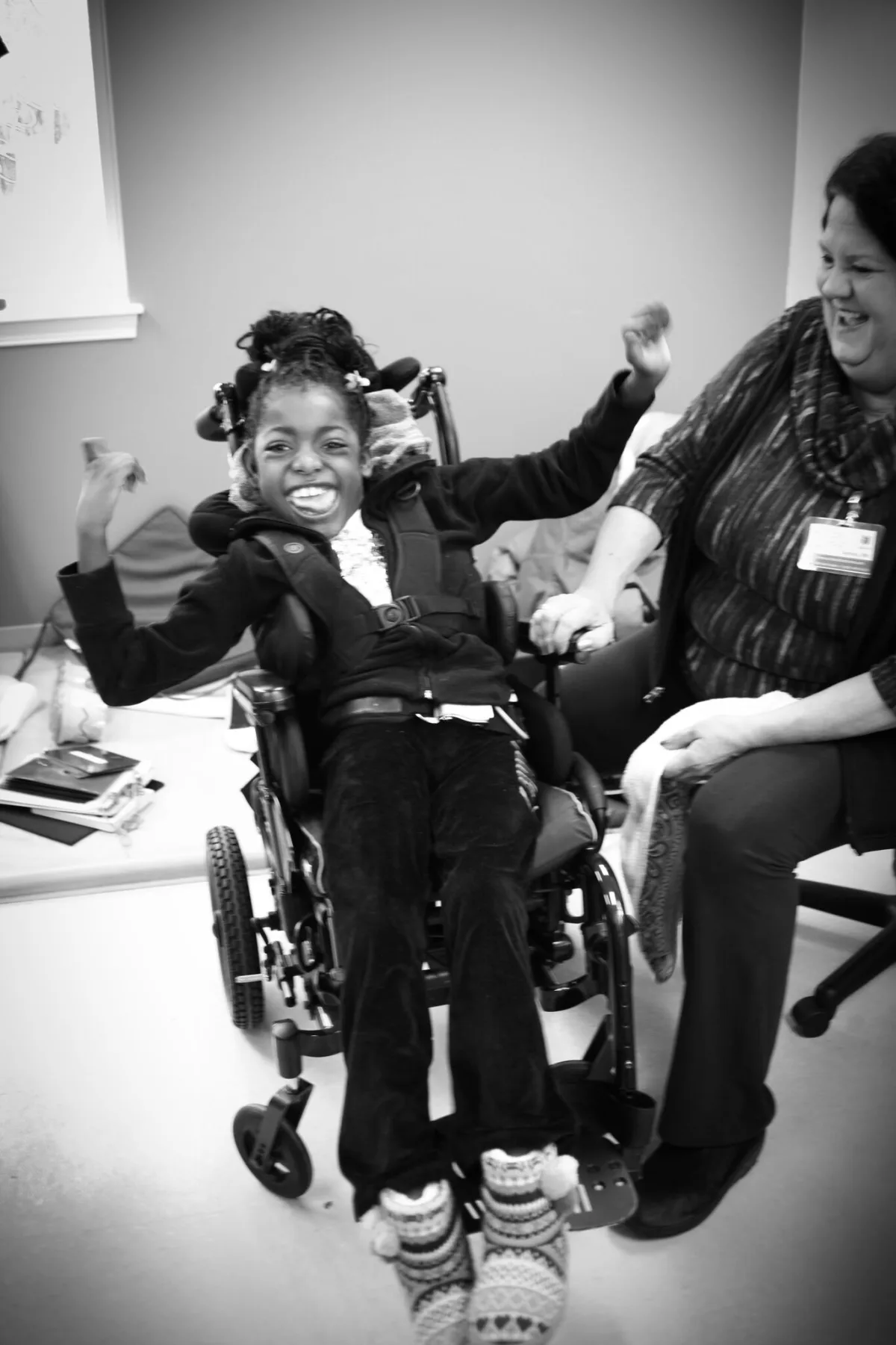 A smiling child in a wheelchair with a caregiver – COR Health pediatric behavioral health services